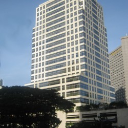6750 Ayala Avenue is a tall white building with multiple windows under a clear blue sky. Taken while riding a bus traversing the side of Ayala Avenue opposite that of Landmark and Glorietta.