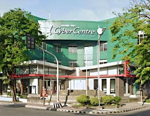 Negros First Cyber Centre, a three-story low-rise building with mostly green facade as seen from the opposite corner of Hernaez and Lacson. The ground floor of the building is now occupied by a branch of Jollibee fastfood.