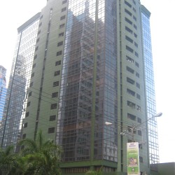 The Centerpoint Building is a tall cuboid structure with a facade of green-painted concrete and dark glass panels. This photo was taken while standing on the sidewalk along Julia Vargas Avenue.