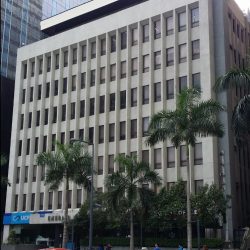 The Emerald Building is a low-rise blocky building with a facade of rows of small rectangular glass windows surrounded by gray concrete walls.