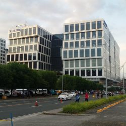 Five E-com Center has rows of rectangular glass pane windows. The middle and the top floors are protruding from the rest. This is the view from Palm Coast Ave. cor Pacific Drive. It has rows of rectangular glass pane windows. The middle and the top floors are protruding from the rest.