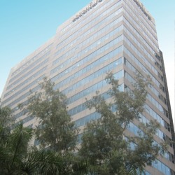 Global One Center is a tall cuboid structure with an exterior of alternating bands of glass panels and gray concrete. This is the building, as seen from the segment of Eastwood Palm Tree Ave. between E-commerce and Citywalk 1.