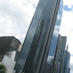 GT Tower has an angular design with sharp angles and diagonal patterns. Its exterior is covered in blue glass panels, and the top has triangular fins, giving it an obelisk-like appearance. Photo taken from the sidewalk at the corner of Ayala Avenue and Amorsolo St.