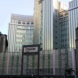 Back of Insular Life Building: the upper floors have a metallic gray facade of vertical strips with narrow windows between them. This is the view from Valero St. parallel to Valero Access Road 3 near Sedeño St.