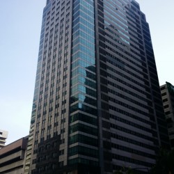 Jollibee Plaza has a block structure and an exterior made of concrete and dark green glass panels. This photograph was taken from the intersection of F. Ortigas Jr. Road and Garnet Road.