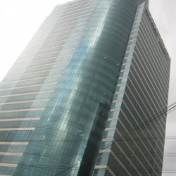 MDC 100 is a cuboid structure with a cylinder inserted in one corner. The cuboid has alternating rows of concrete and glass, while the cylinder's facade is all glass panels. The picture was taken from the lower staircase levels on the other side of E. Rodriguez Ave. The staircase is the access to the footbridge connecting both sides of E. Rodriguez.