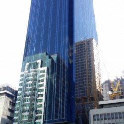 The Orient Square is a tall cuboid building with a facade of blue glass panels and maroon marble tiles. This is Orient Square, as seen from the parking between Emeral Avenue and Garnet Road near Julia Vargas Ave.