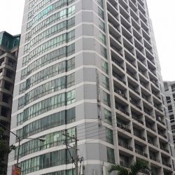 The Pacific Center has glass panels with a white concrete facade on all floors except the two lowest stories. This picture shows the view from the sidewalk on the other side of San Miguel Ave.
