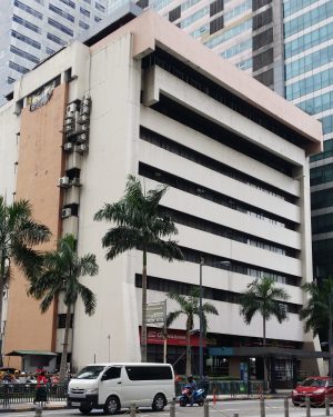 Padilla Building is a low-rise structure with a simple blocky appearance. Its facade is mainly that of a light gray concrete with narrow horizontal strips of recess covered by glass windows. The top of the building has an orange concrete protrusion. There is also an orange vertical concrete cover on the side.