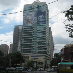 The Philippine AXA Life Center has an exterior made of horizontal bands of glass and white concrete. It also has a pyramidal steel spire on top. The picture was taken from the sidewalk at Malugay St. cor. Ayala Avenue.