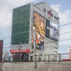 PRC Tower is a blocky building with green glass panels in front and gray concrete walls on the sides. This PRC Tower is seen from a moving bus on the other side of the MRT railways.