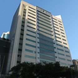 The facade of PSBank Center is predominantly composed of white concrete, interspersed with narrow strips of glass windows on each level. This view is from Paseo De Roxas cor. Ayala Ave. on the sidewalk adjacent to Ayala Tower One.
