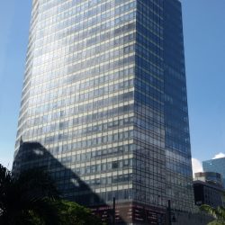 The Philippine Stock Exchange Tower is an L-shaped building with a blue glass facade.