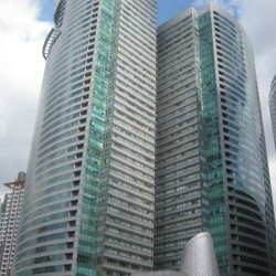 RCBC Plaza is a skyscraper complex that has two towers with alternating horizontal bands of gray tiles and reflective glasses mounted on a common podium structure. This is RCBC Plaza, seen from the sidewalk along Salcedo St. between Ayala and Dela Rosa.