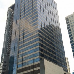 A.T. Yuchengco Centre is a tall square prism covered with beige and blue glass panels. Its lower floors have an exterior of a gray concrete podium. The picture was taken from 5th Ave. cor 26th St. in front of Six Neo.