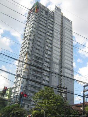 tall multi-story building with staggered facade and overhead power lines in the foreground.