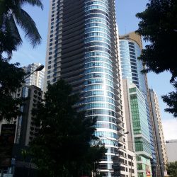 The Malayan plaza has a blue glass exterior. It has a tall block shape with an overlapping cylinder in one corner.