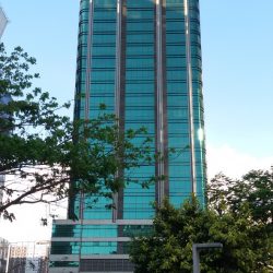 The upper floors of The Trade and Financial Tower have a rectangular-shape overall structure. From the Track 30th, where this shot was taken, the side that can be seen here has a facade made of green glass windows divided by vertical maroon and white segment. The top two floors have white horizontal protruding segments above, below, and between them. The lower levels with the wider area also have white horizontal segments between them. The top two among these floors have the same green glass windows, the ground floor has transparent glass walls, and the levels between them have walls made of maroon concrete.