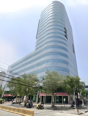 Times Plaza has an exterior of alternating horizontal bands of gray concrete and glass panels. It has lower podium levels with more extensive floor areas and higher tower levels with smaller floor areas. This is Times Plaza, as seen from the island dividing Taft Avenue under LRT railways near its intersection with UN Avenue.